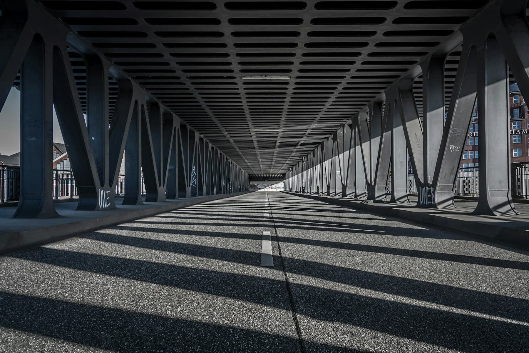A steel bridge casting repeating structural shadows