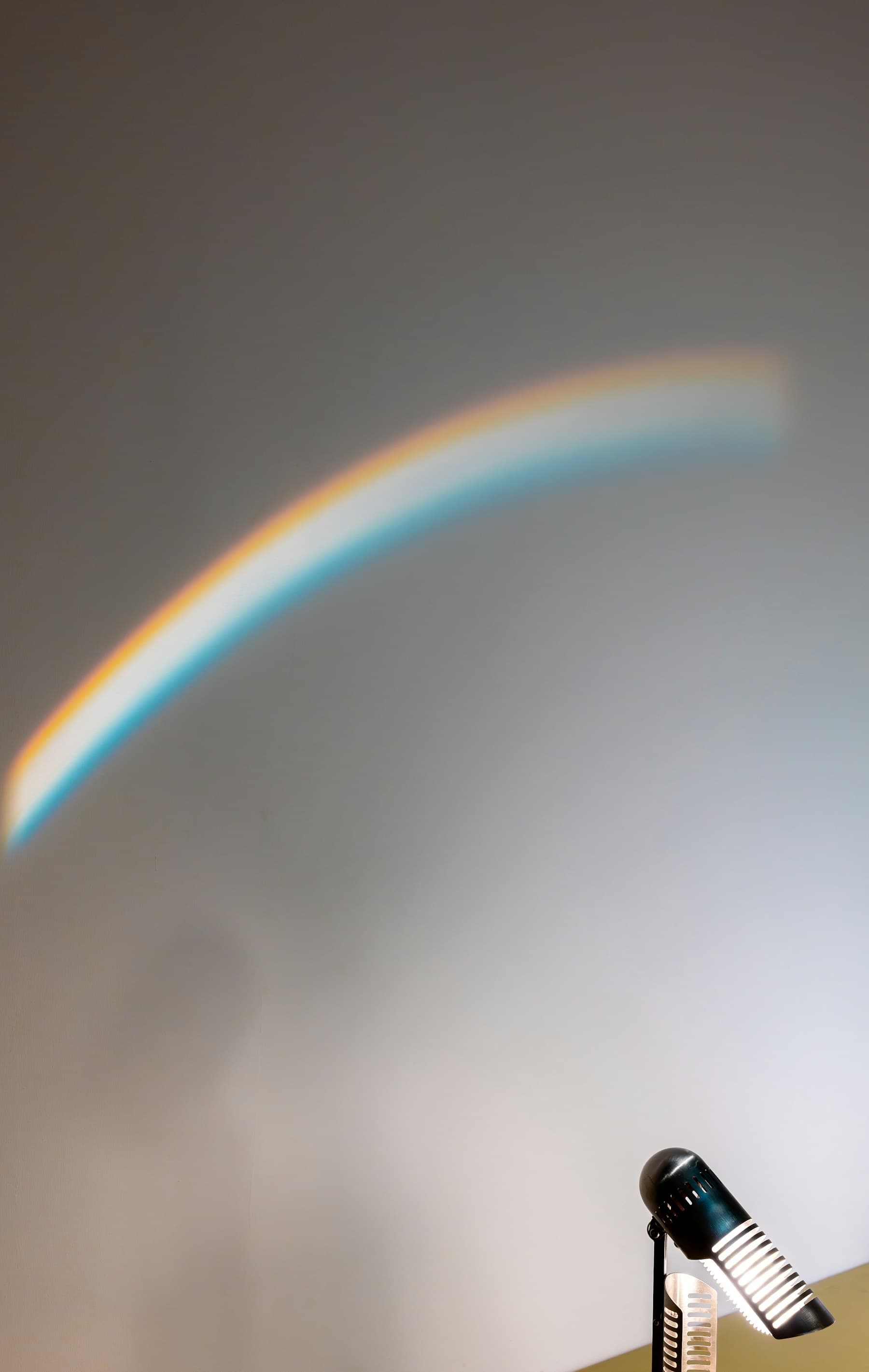 A physical rainbow arc crossing a pale wall