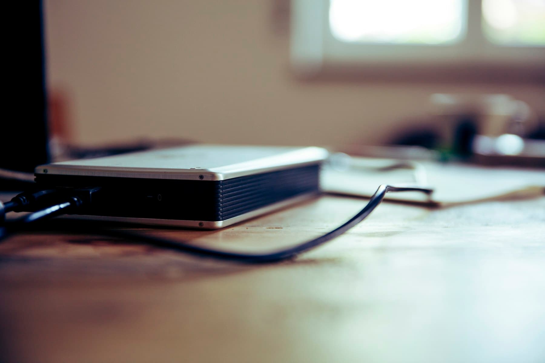 A metal network device and cable beside a bright window