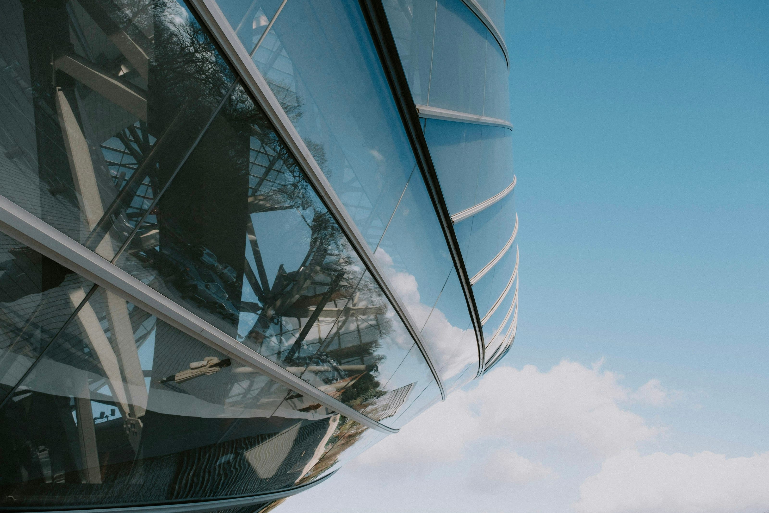 A glass structure holding the reflection of a bright sky